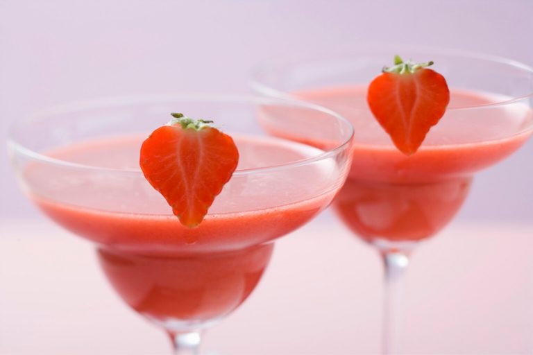 2 glasses of strawberry daiquiri gardnished in strawberry halves