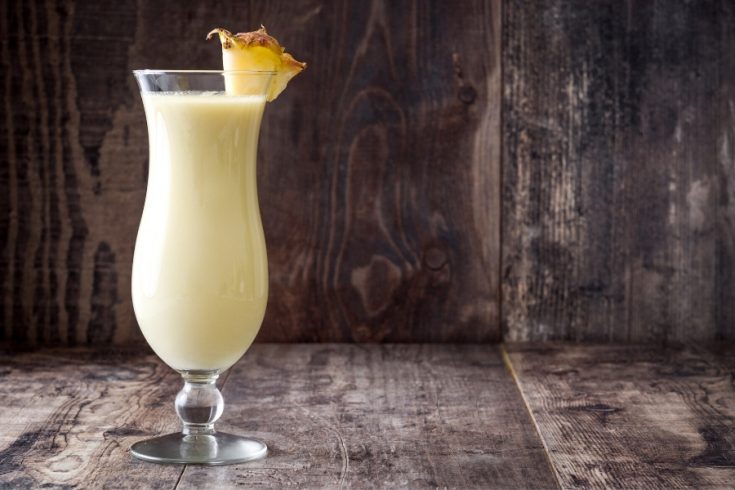 creamy tall glass of Pina Colada with a slice of pineapple