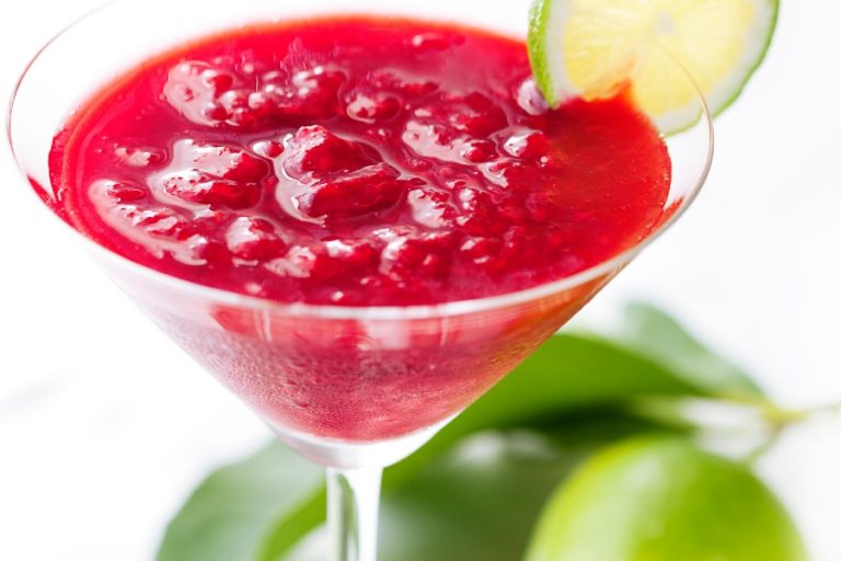 a glass of raspberry daiquiri cocktail with a slice of lime
