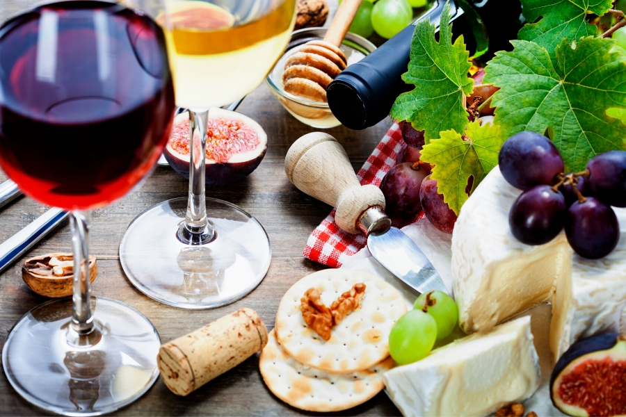 A table full of cheese, biscuits and red and white wine