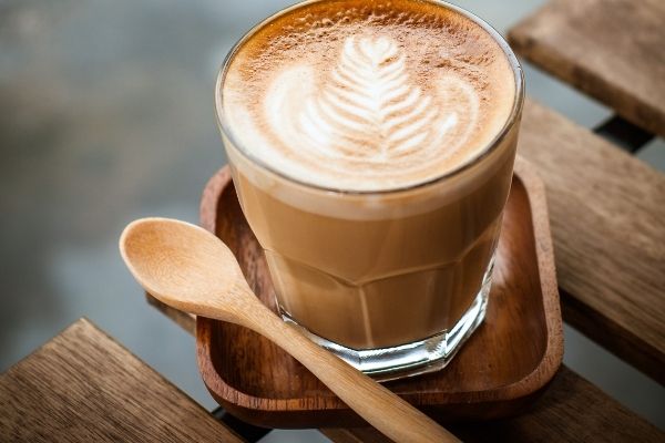 a close up of a breve latte with wooden spoon