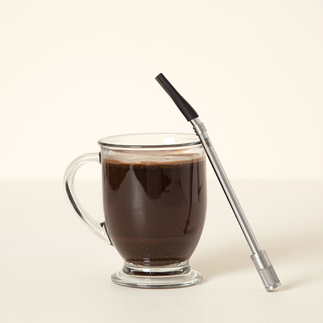 coffee straw with filter resting on a coffee cup